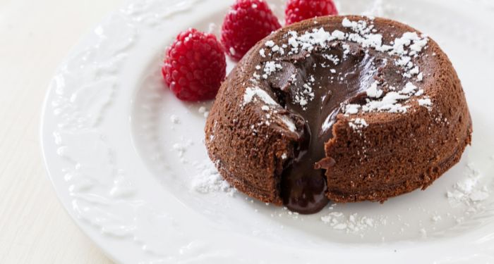 lava cake with powdered sugar and raspberries on the side
