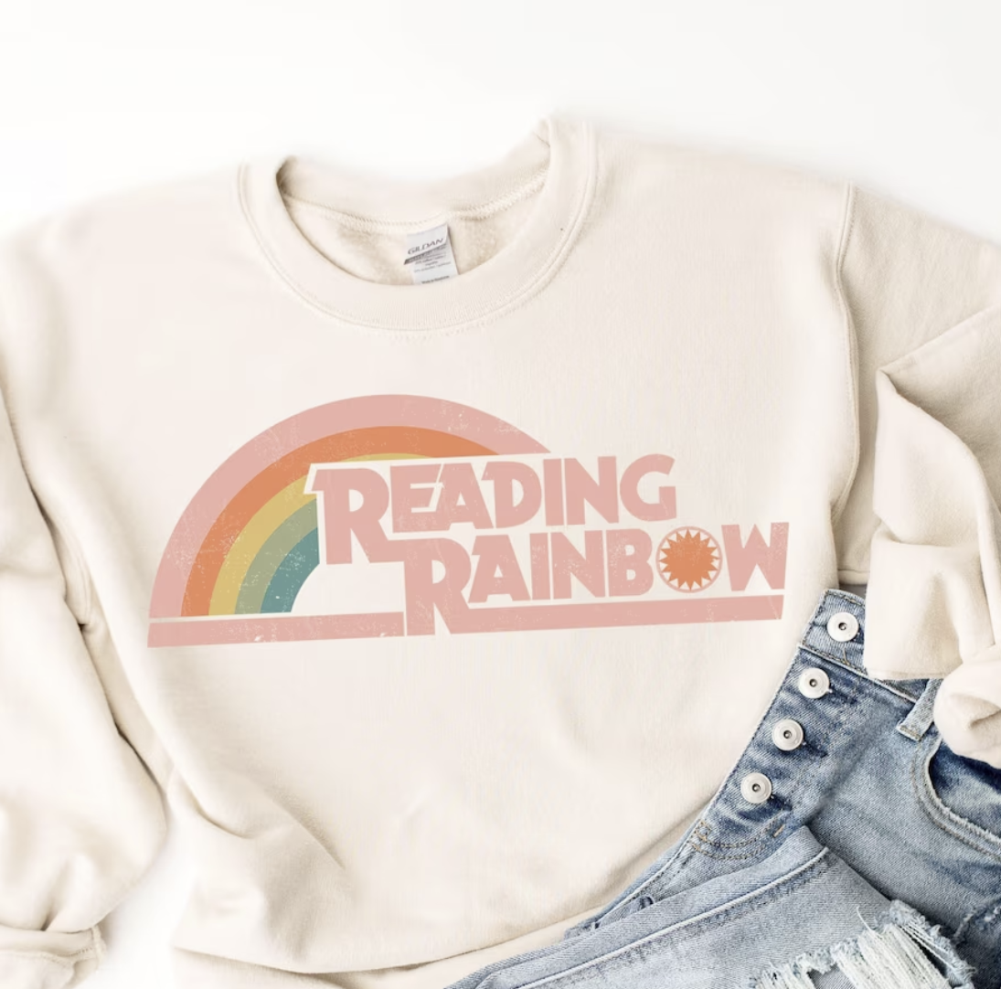 Cream colored sweatshirt with a pastel rainbow and the words "READING RAINBOW" in pink