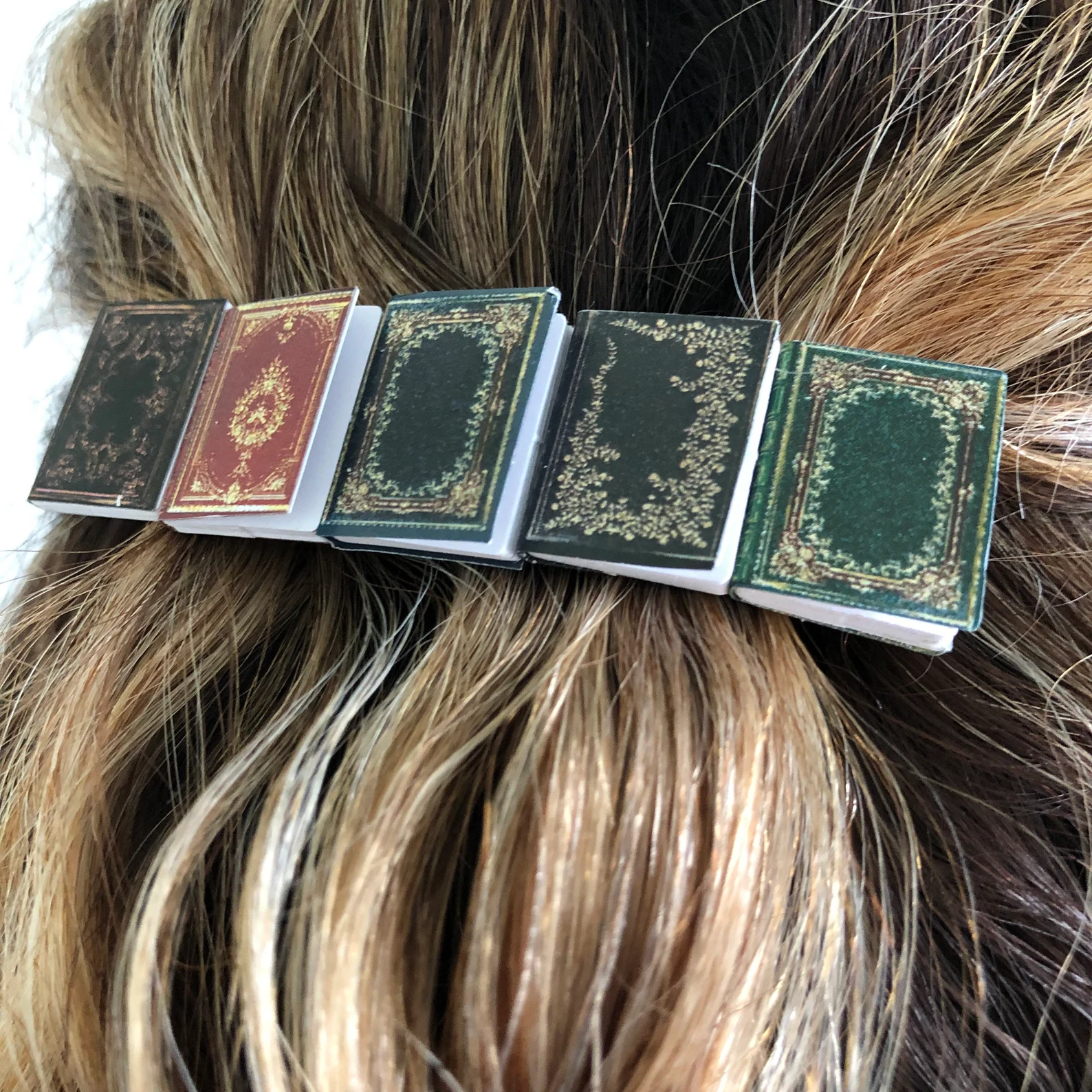 a photo of a five miniature books set on a hair clips, creating such a cute literary hairstyle