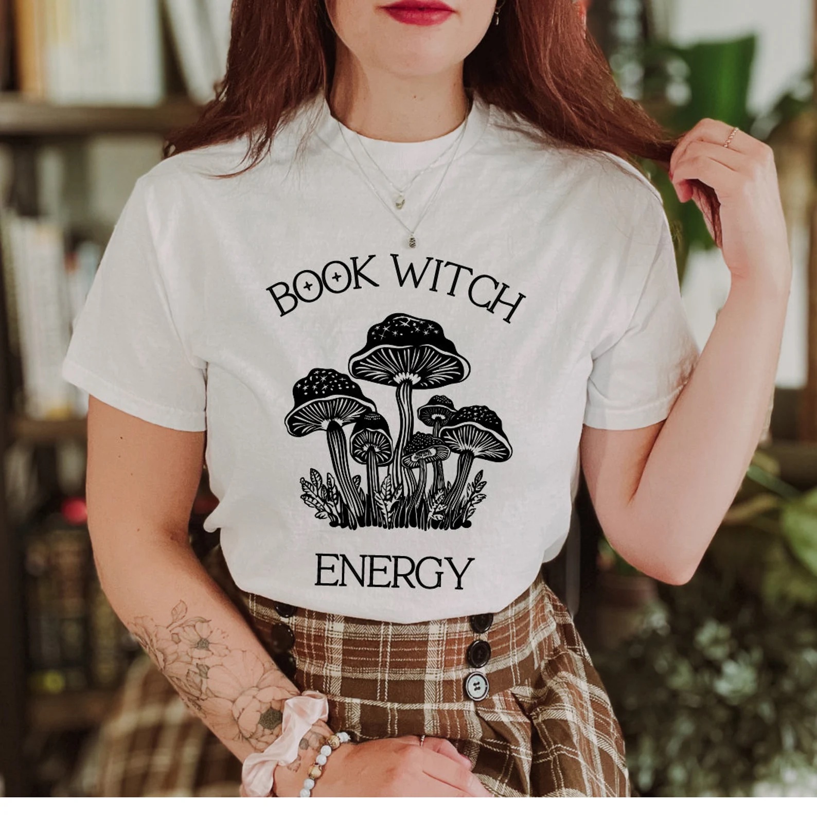 a photo of a white woman wearing an off-white shirt that says "Book Witch Energy"
