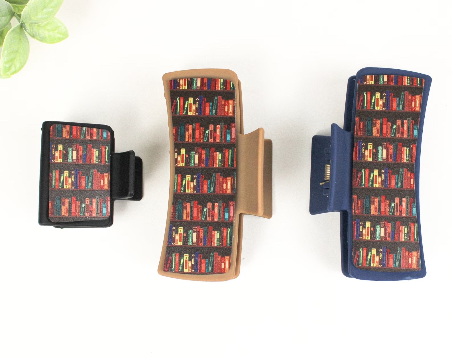 a photo of three hair clips each depicting a print of bookshelves 