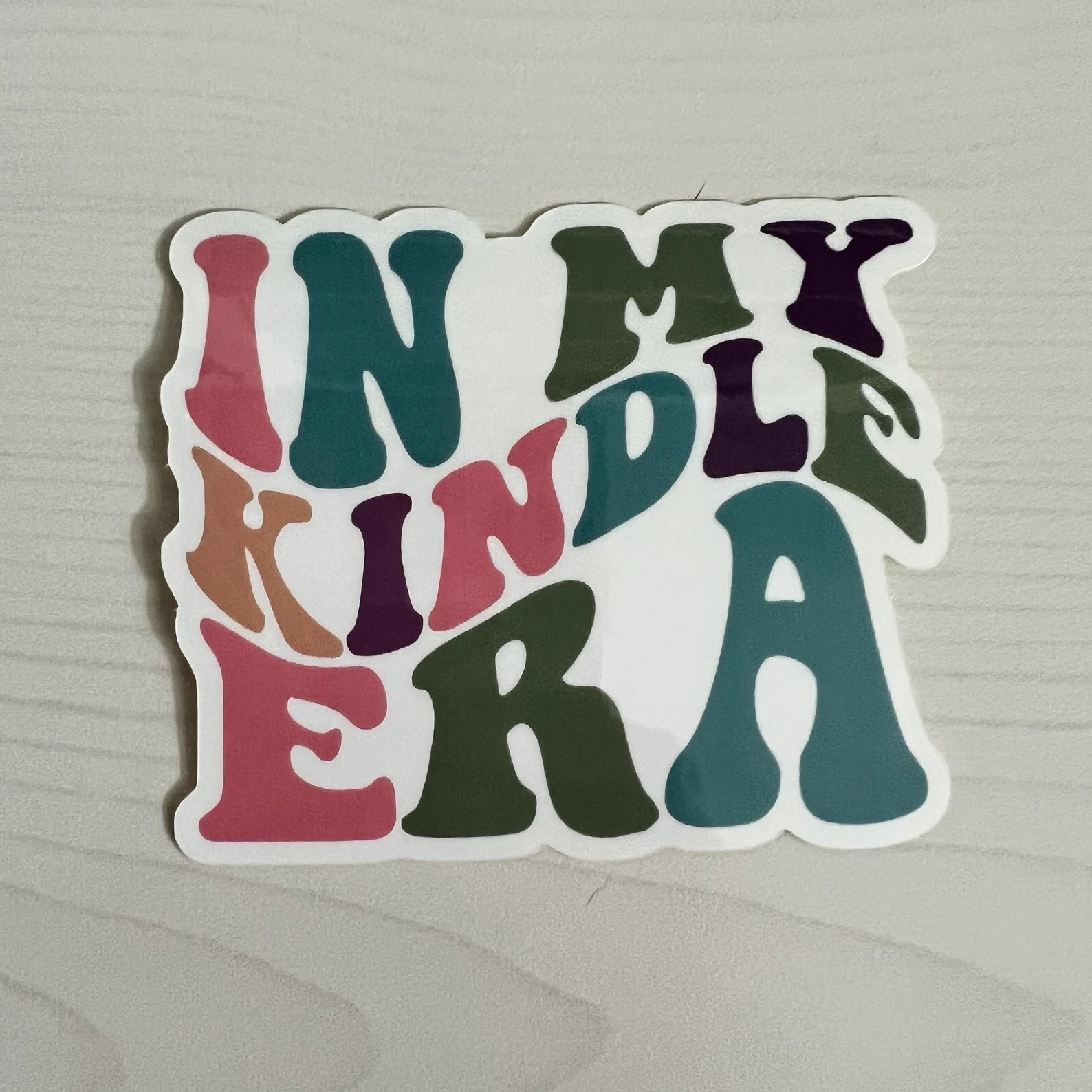 a photo of a sticker that says "In My Kindle Era"