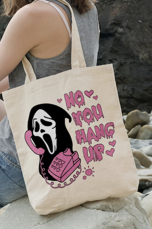 beige tote bag with a graphic print of the killer from Scream holding a pink phone saying "no you hang up"