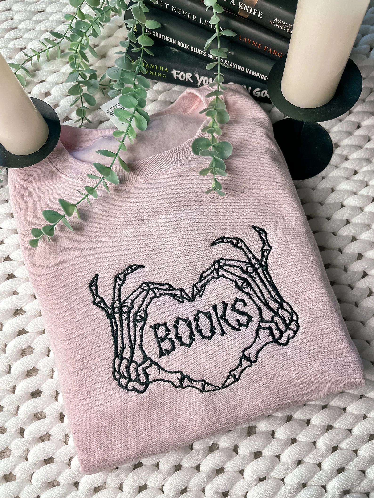 pink sweatshirt with he word "books" between two skeleton hands making a heart shape.