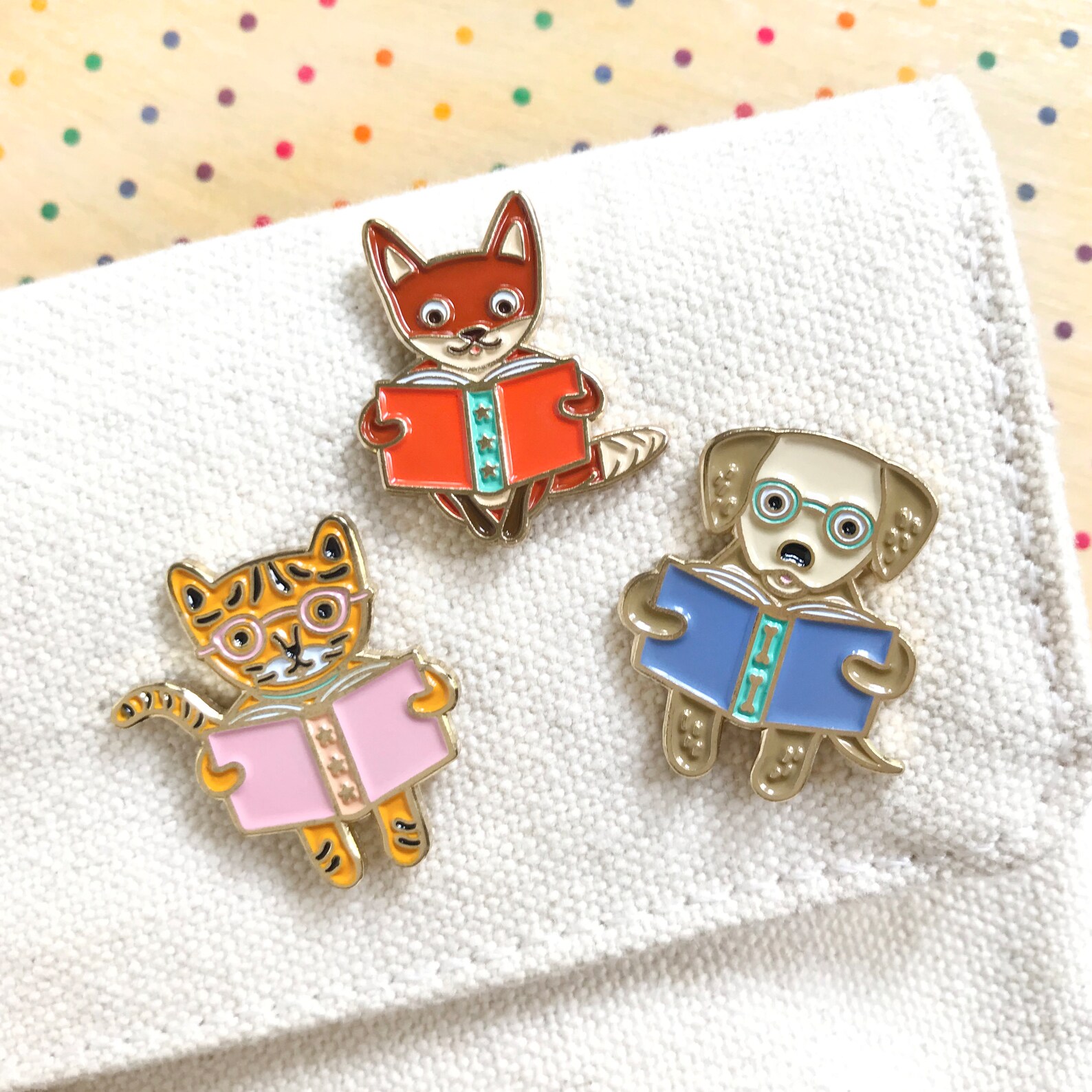 set of three enamel pins in the shape of animals reading