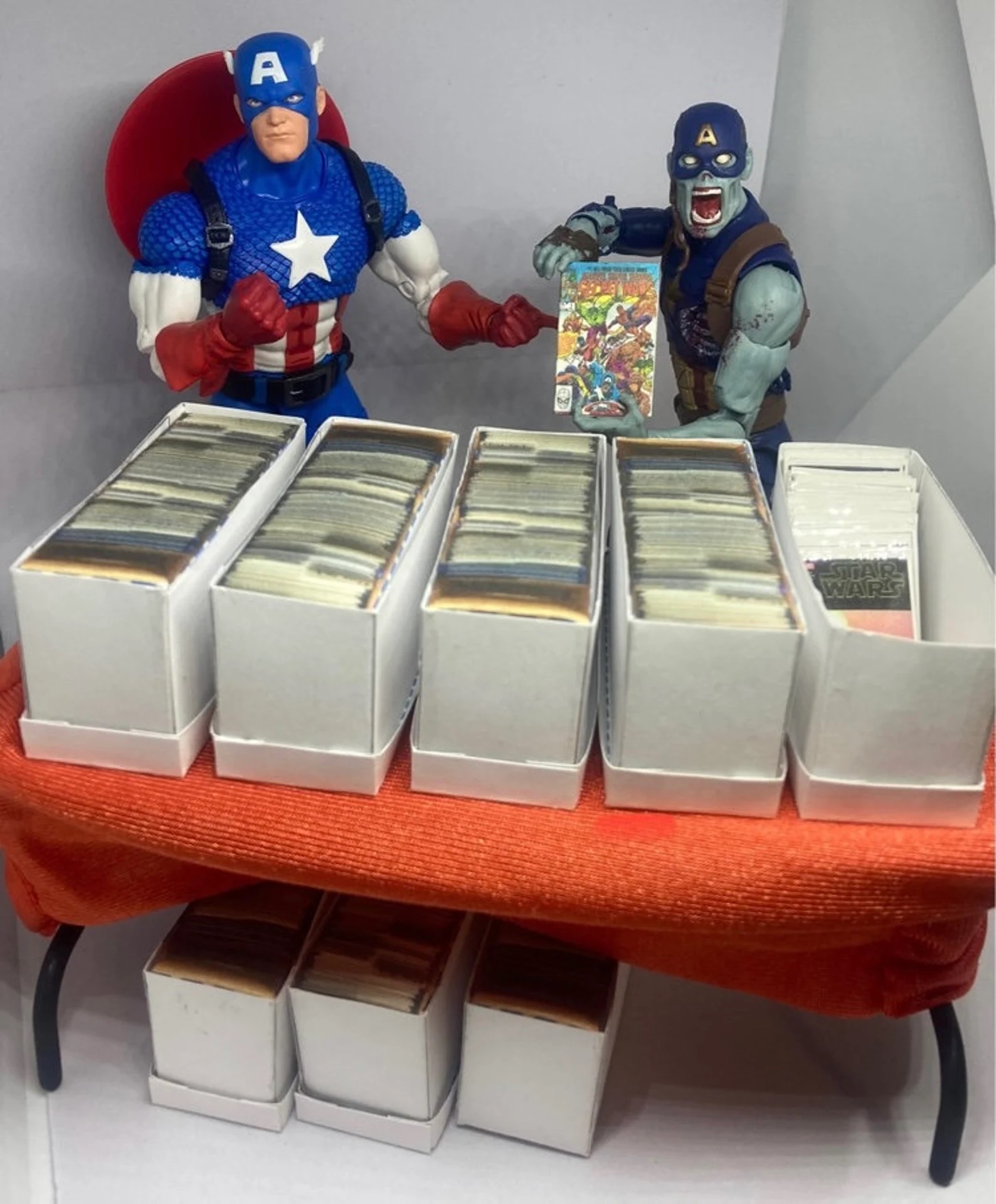 Two action figures of Captain America show off doll-sized comics lined up in doll-sized longboxes