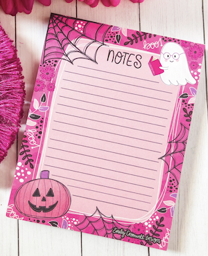 pink notepad with illustrations of a pumpkin and ghost reading a book