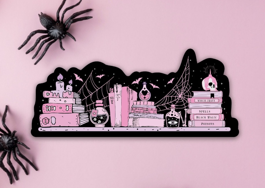 Black and pink sticker with spooky items on it, including stacks of pink books.