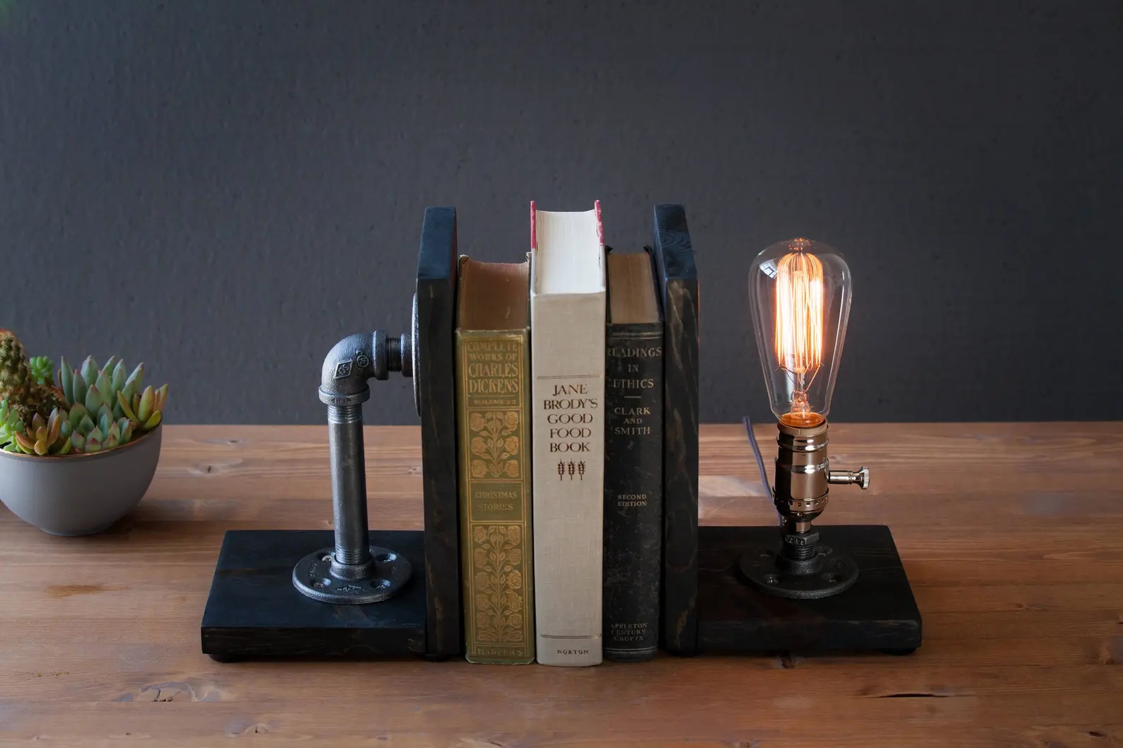 a photo of a bookend of a pipe of the left side and a n exposed light bulb on the right
