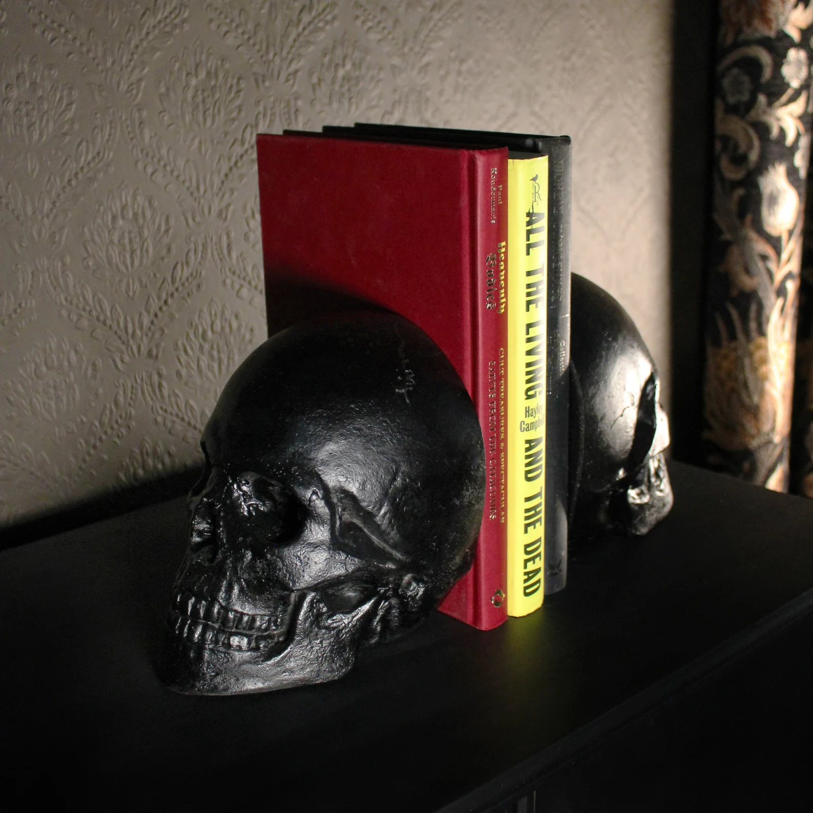 a photo of black skull bookends on a black bookshelf