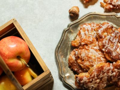 a plate of apple fritters next to a container of fresh apples