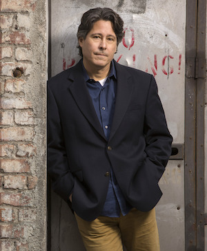 author Robert Dugoni leaning against a brick wall 