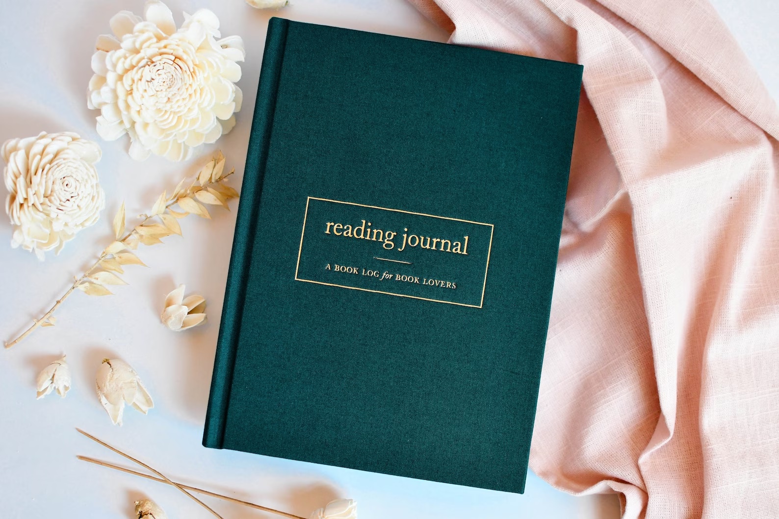 a photo of a hardback reading journal with gold embossing that says "reading journal" across the front.