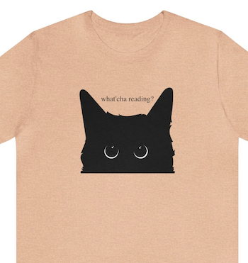 a t-shirt with an image of the top of a black cat's head and the text "Watcha Reading?"