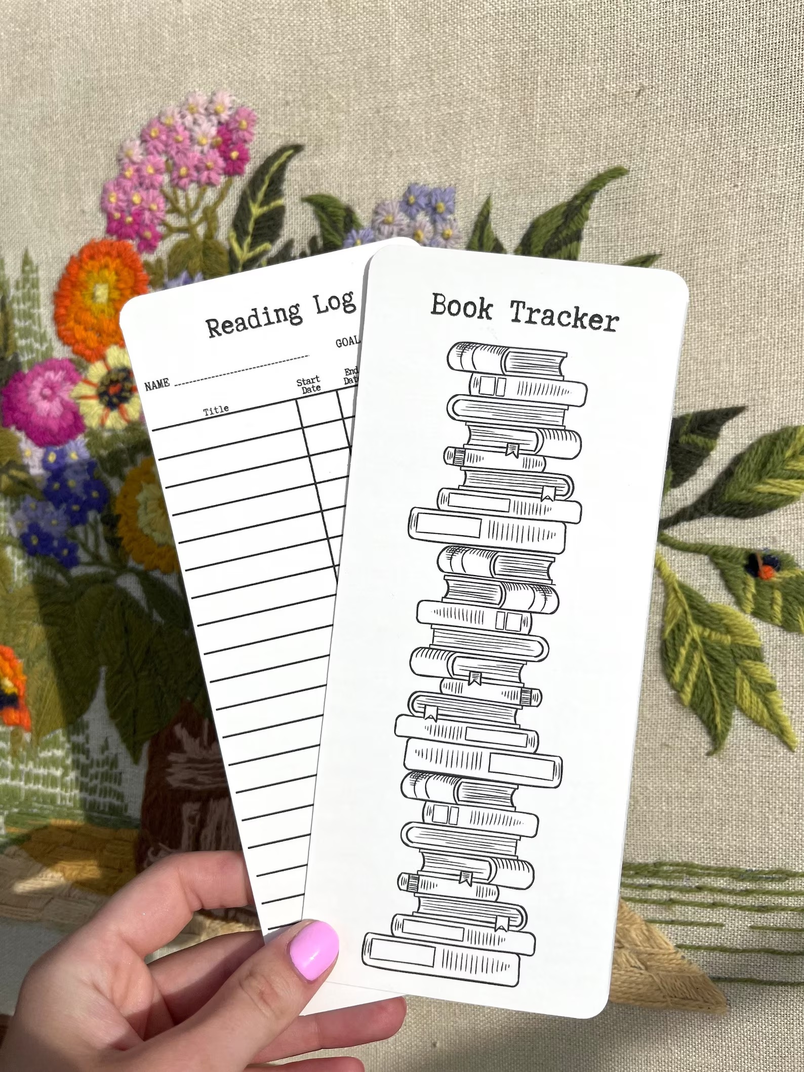a photo of a bookmark featuring a reading tracker on one side and a pile of book spines for you to fill in