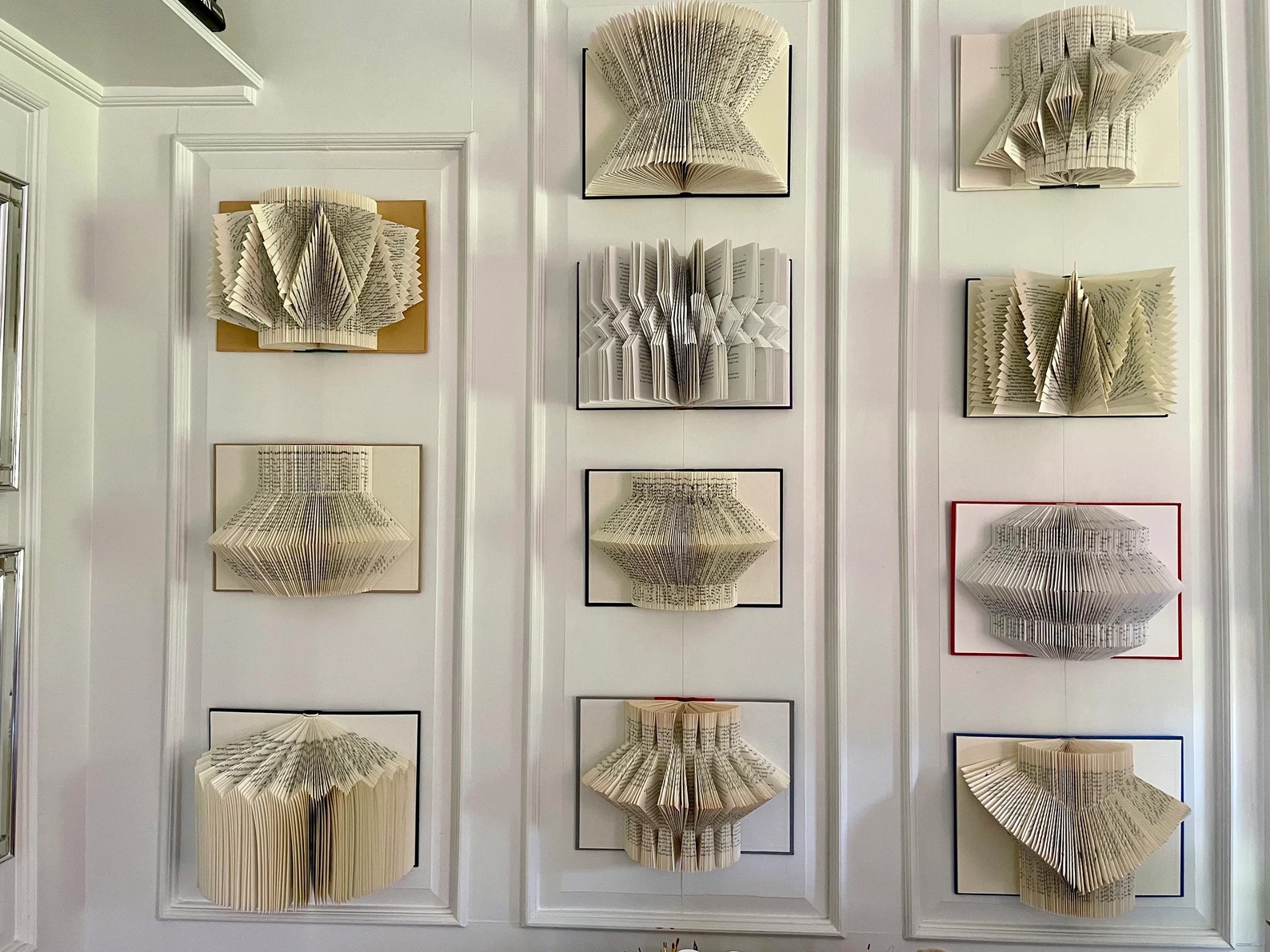 a photo of a gallery wall of books whose pages are folded in different creative ways.