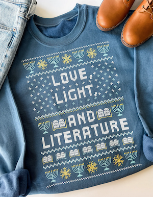 blue sweatshirt with graphics of stars and menorahs that says "love, light and literature"