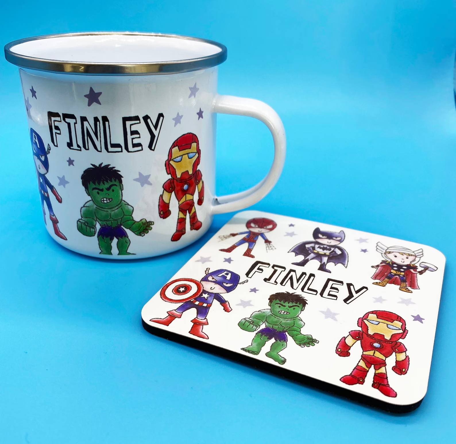 A white, child-sized mug with cartoonish drawings of the Avengers and the personalized name "Finley" in thin block letters. There is also a matching, square coaster