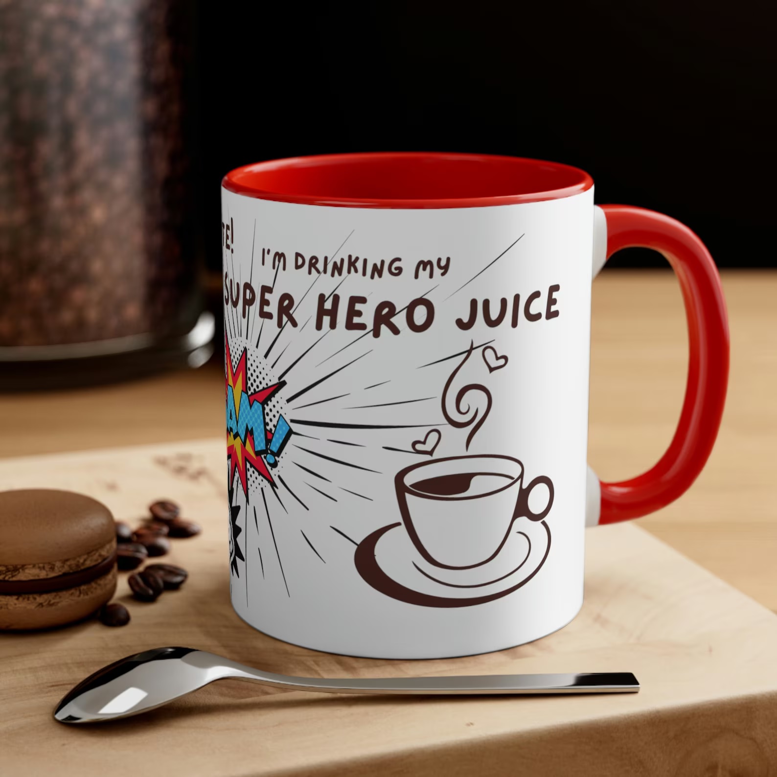 A white mug with a red handle and interior. Comic sans text reads, "Give me a minute! I'm drinking my superhero juice." It is decorated by images of a coffee cup and several onomatopoeias,