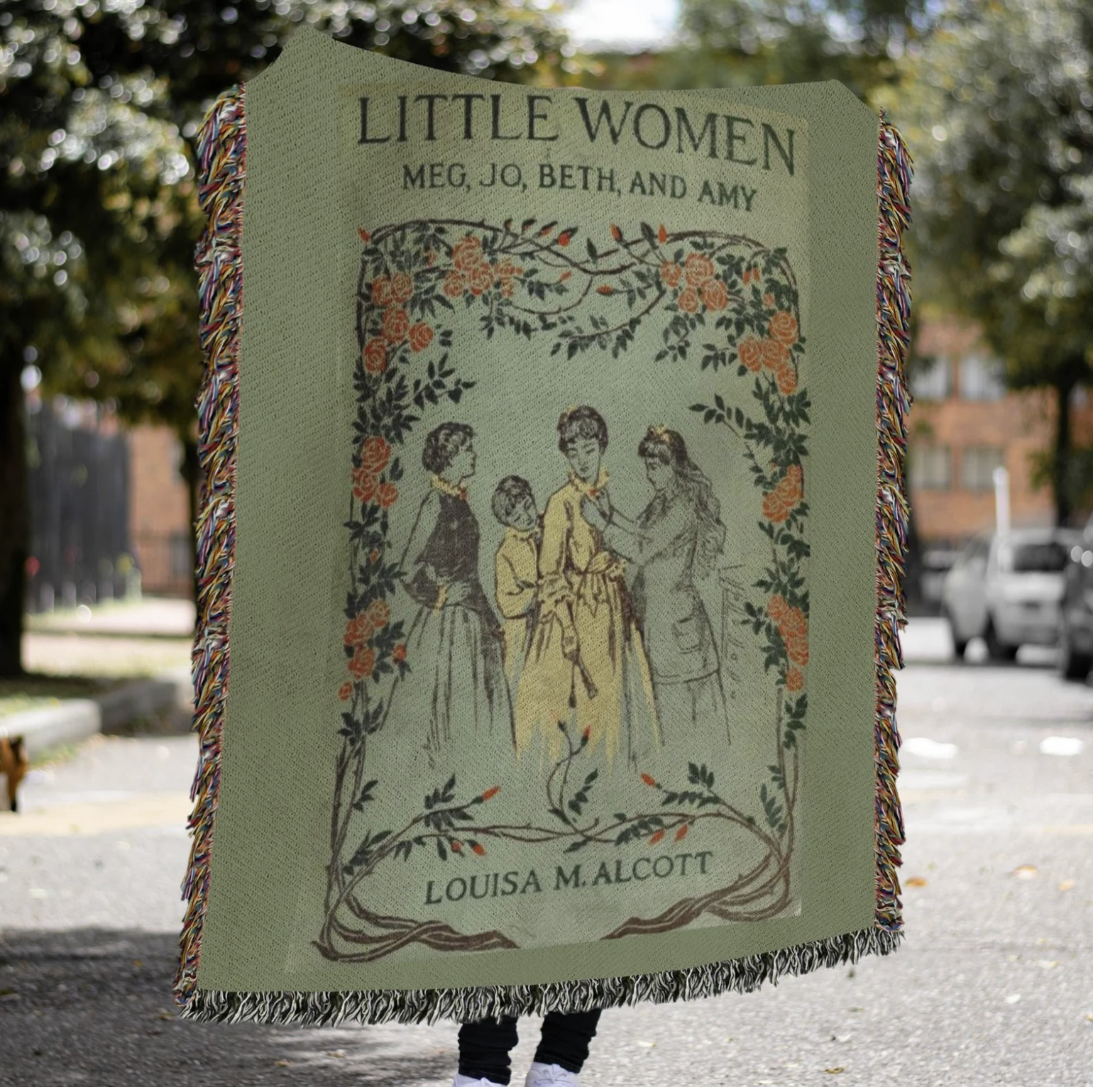 Fern green woven blanket featuring a vintage cover of Little Women with flowers and four young women in 1800s dresses.