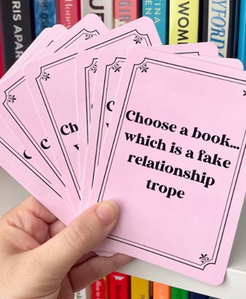 a photo of TBR cards with prompts like "Choose a book...which is a fake relationship trope"