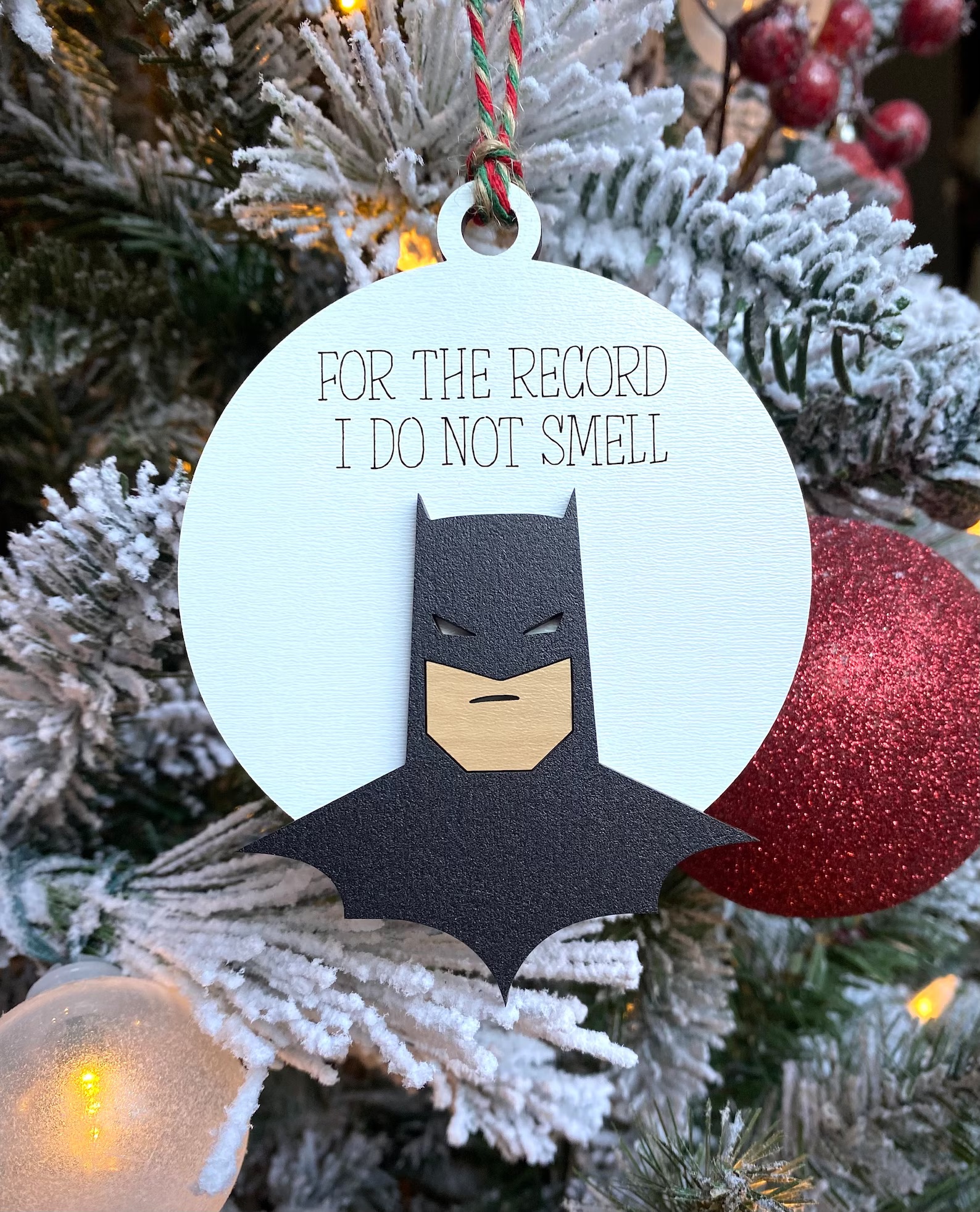 a Batman Christmas ornament with the text "For the record, I do not smell"