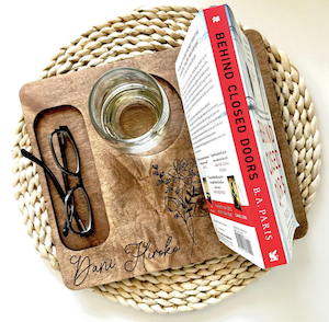 a wooden book stand tray that holds a book, with a spot for a glass and snacks or eyewear