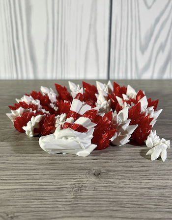a photo of a 3d printed articulated dragon with red and white stripes