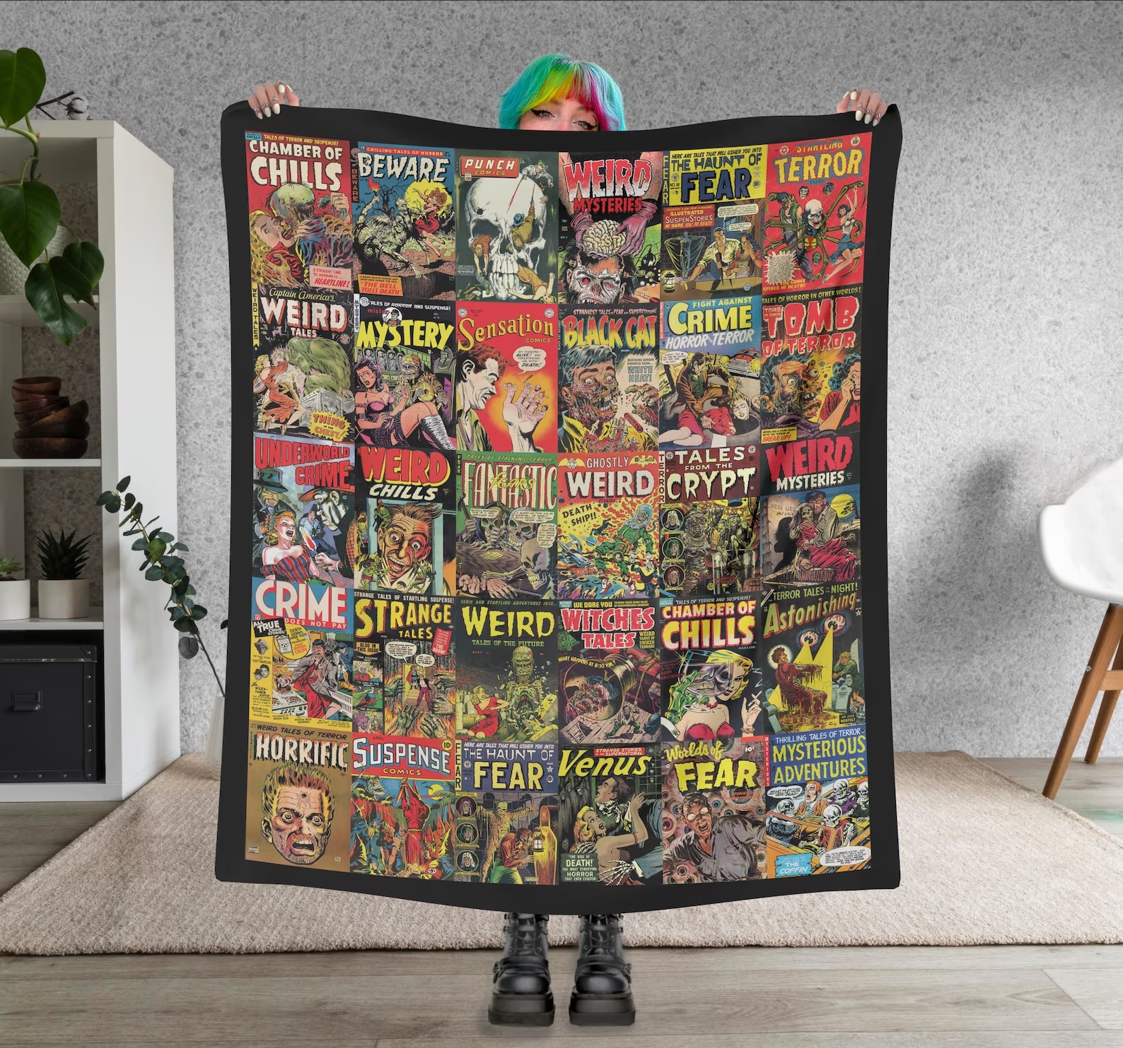 A person holds up a throw blanket featuring images of vintage horror and mystery comic book covers