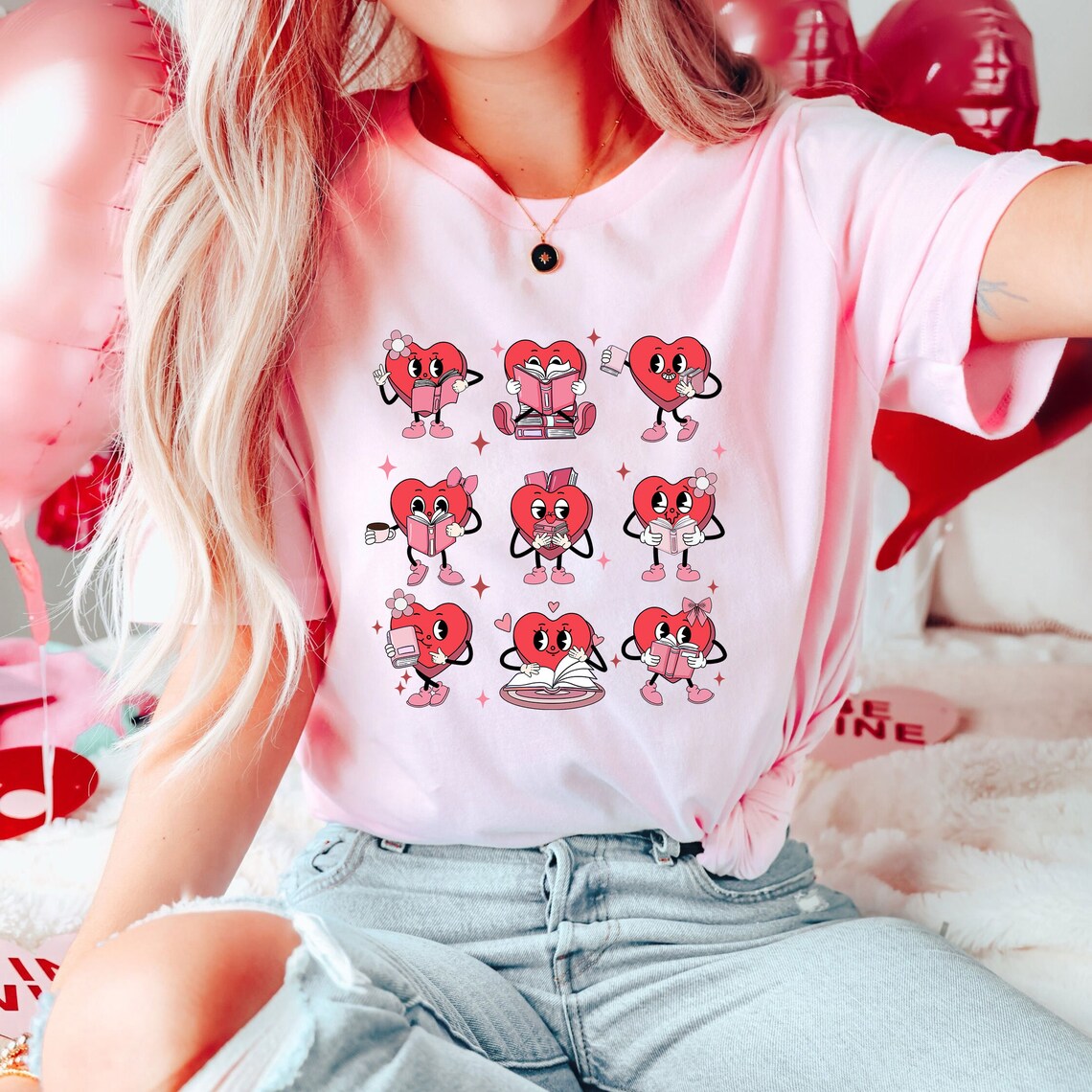 a photo of a pink t-shirt with images of a heart reading a book across it