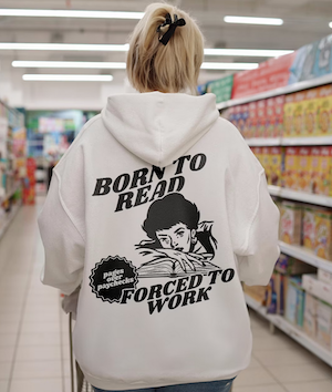 a hoodie sweatshirt with a printed graphic on the back of a woman with an open book and text saying "born to read forced to work"