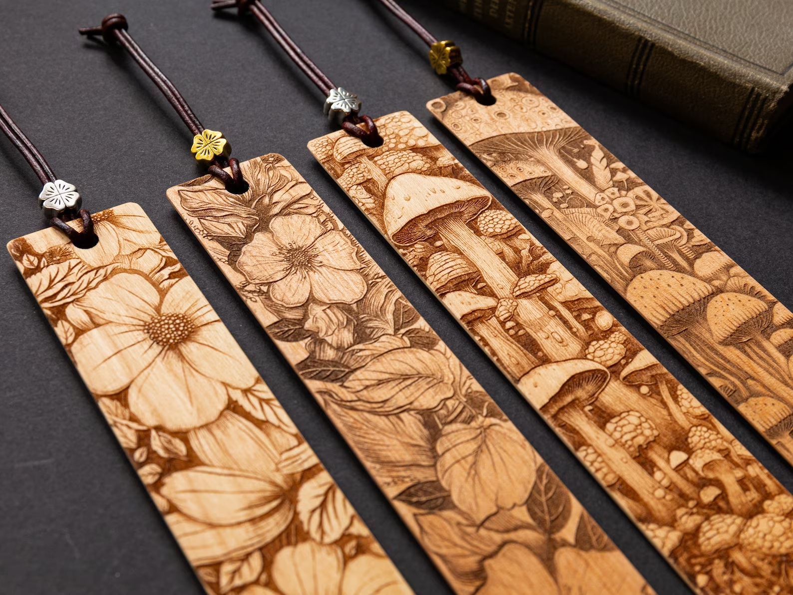 a picture of four wooden bookmarks featuring floral and mushroom designs