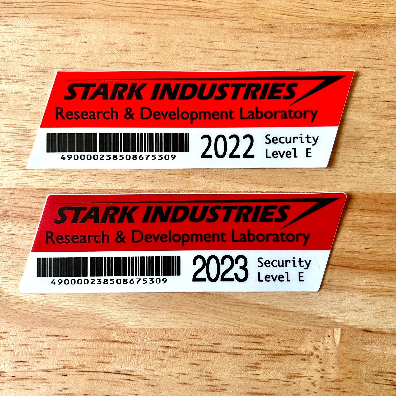 Two red-and-white car decals with the Stark Industries logo and the words "Research & Development Laboratory, Security Level E." One is for 2022, the other for 2023.