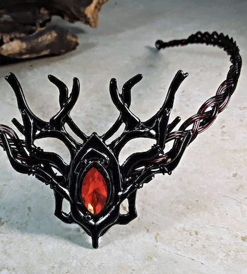 an image of a tiara made of thick black metal in the shape of bare branches with a red jewel in the center