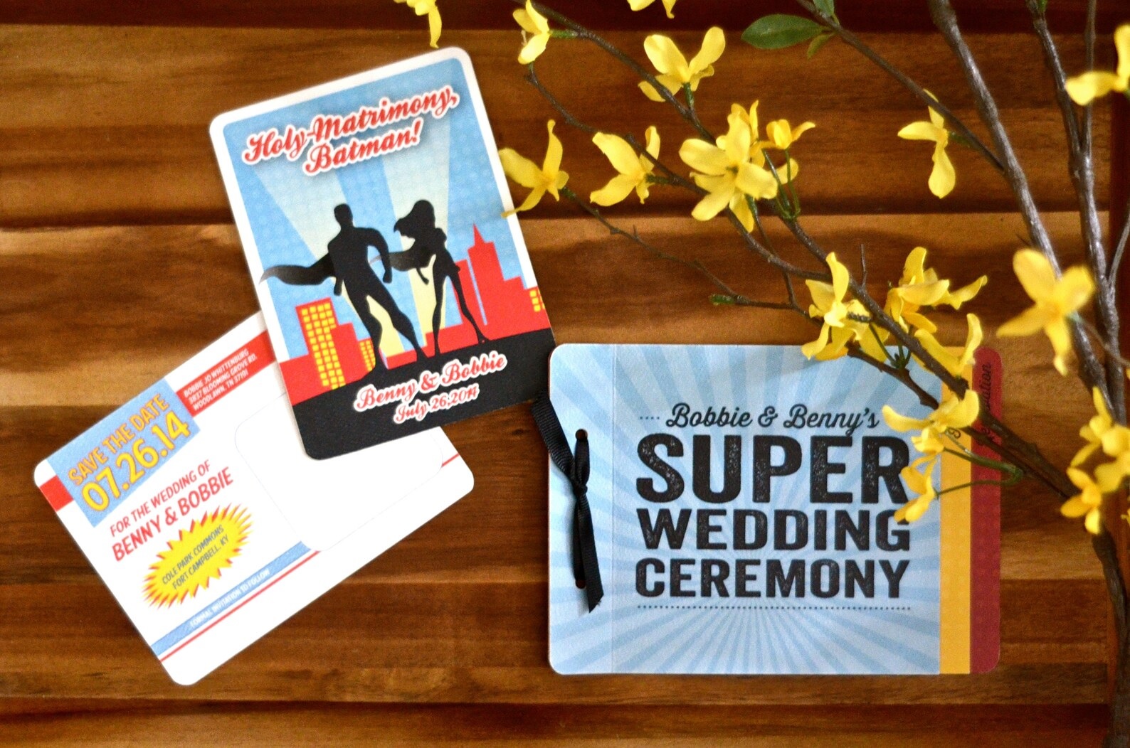 Superhero-themed wedding invitations, featuring silhouettes of a male and female superhero standing side by side