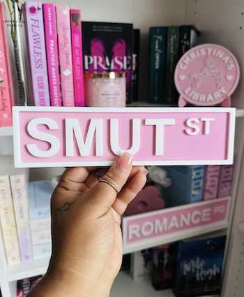 a photo of Bookshelf Street Signs reading "Smut St" and "Romance St"