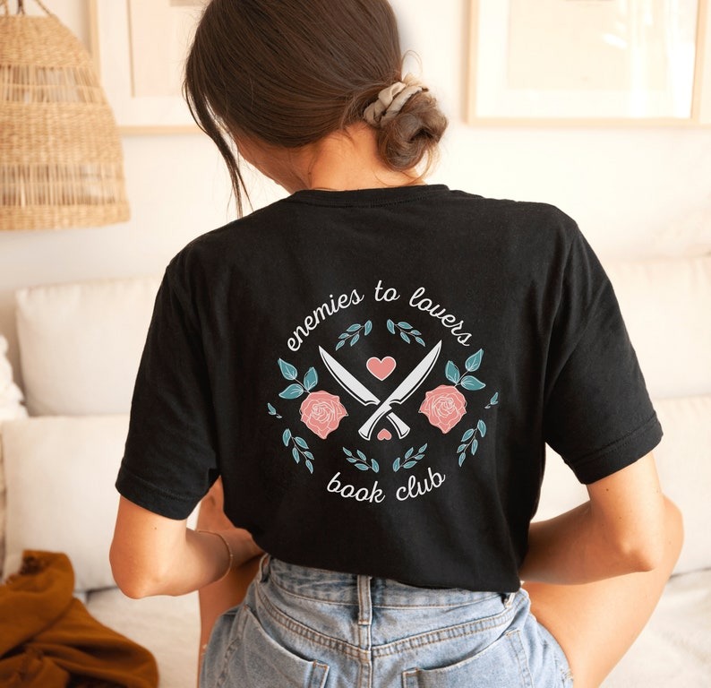 a shirt with a design of crossed knives and roses with the text enemies to lovers book club