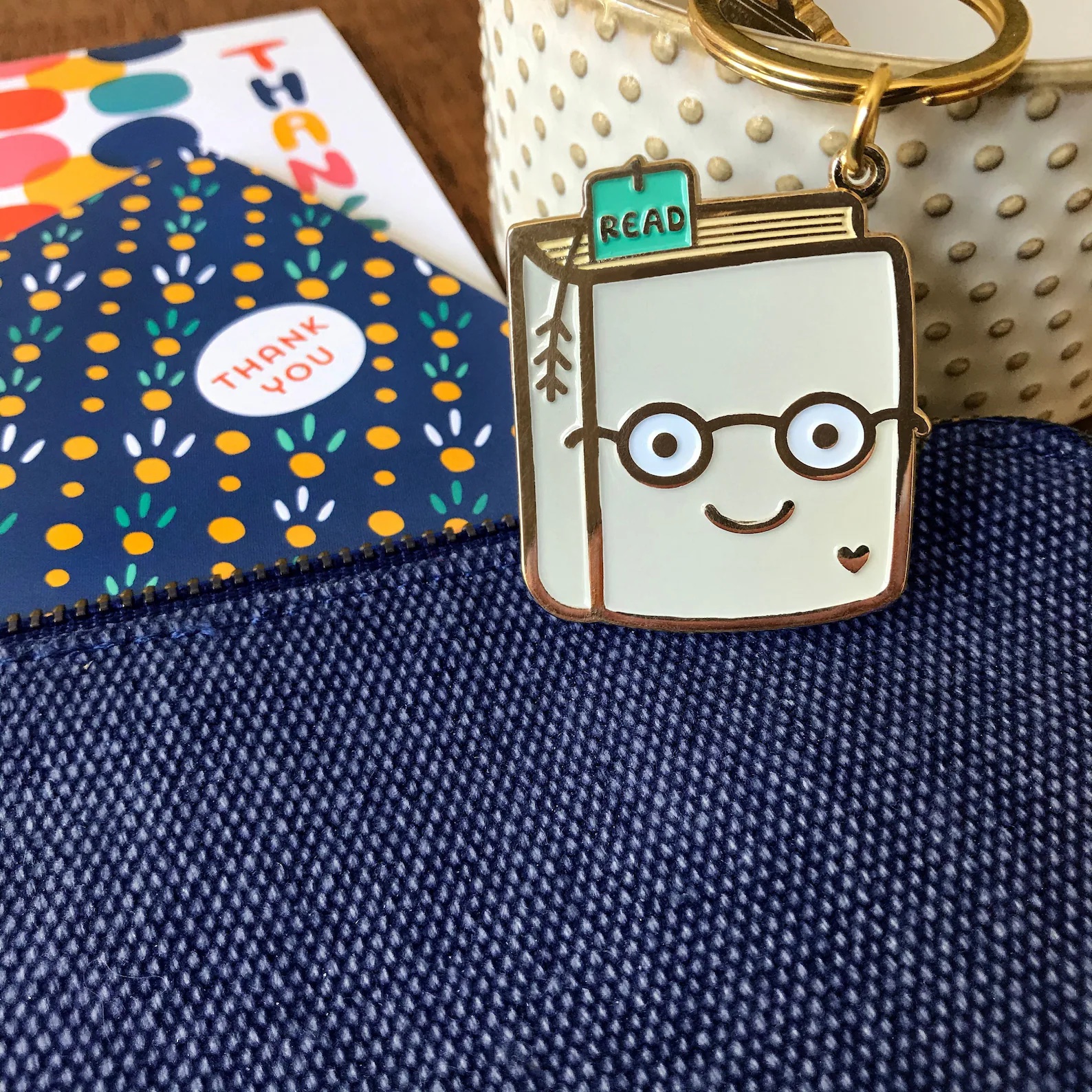 a photo of enamel keychain that looks like a book wearing glasses