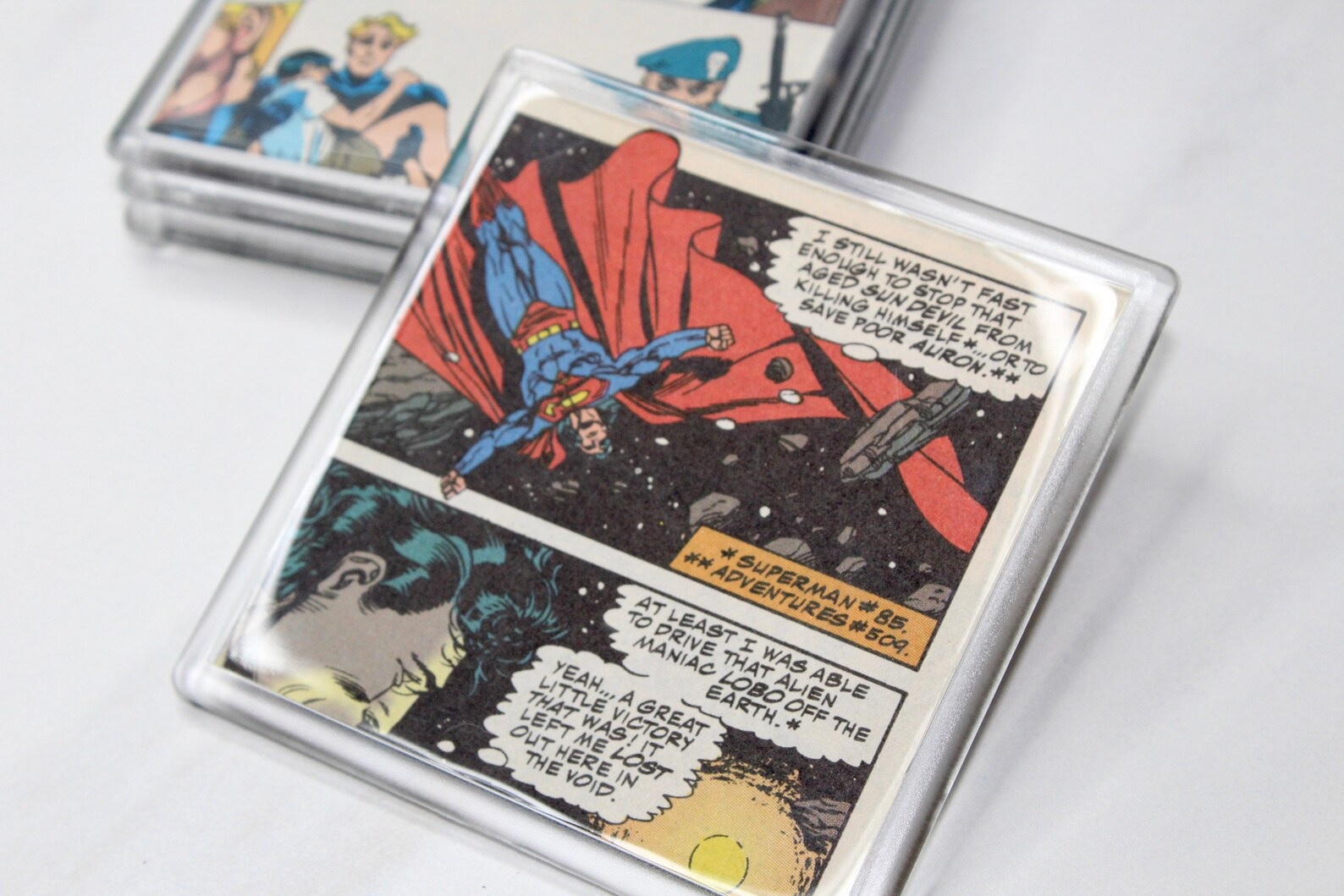 A square coaster featuring one and a half comic book panels of Superman brooding in space