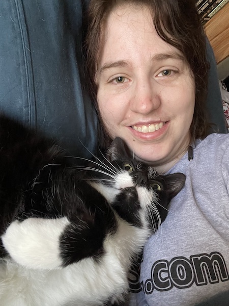 a black and white cat snuggled up under a woman's chin