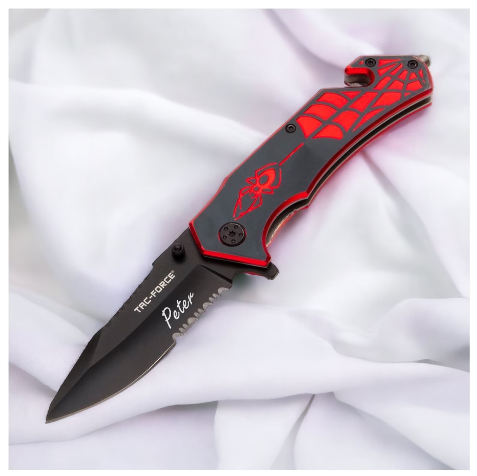 An open pocketknife with a black handle featuring a red, Spider-Man-inspired spider dangling from a web