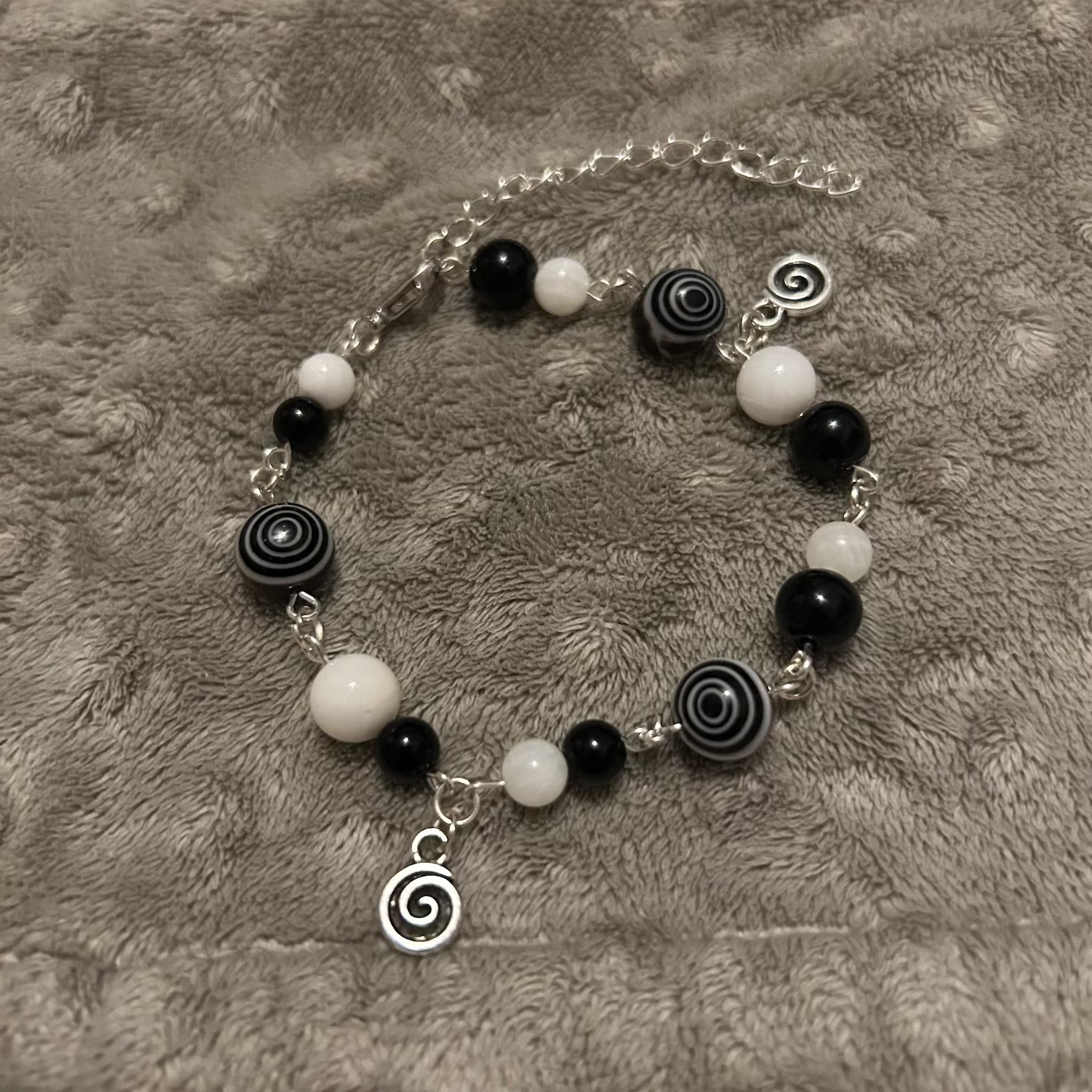 A bracelet made of black and white beads with two spiral charms