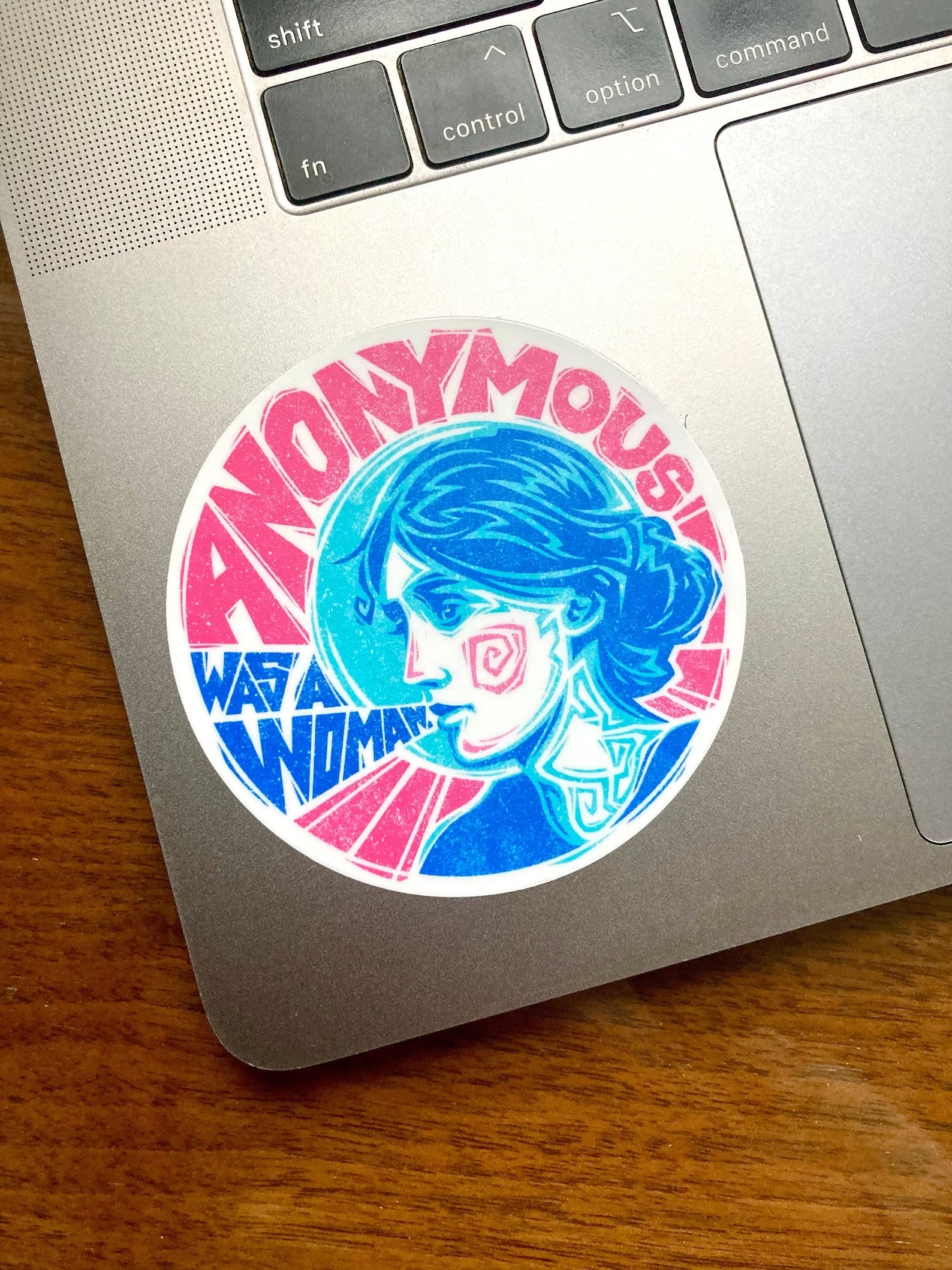 a photo of a sticker that features an illustration of Virginia Woolf along with the quote "anonymous was a woman"