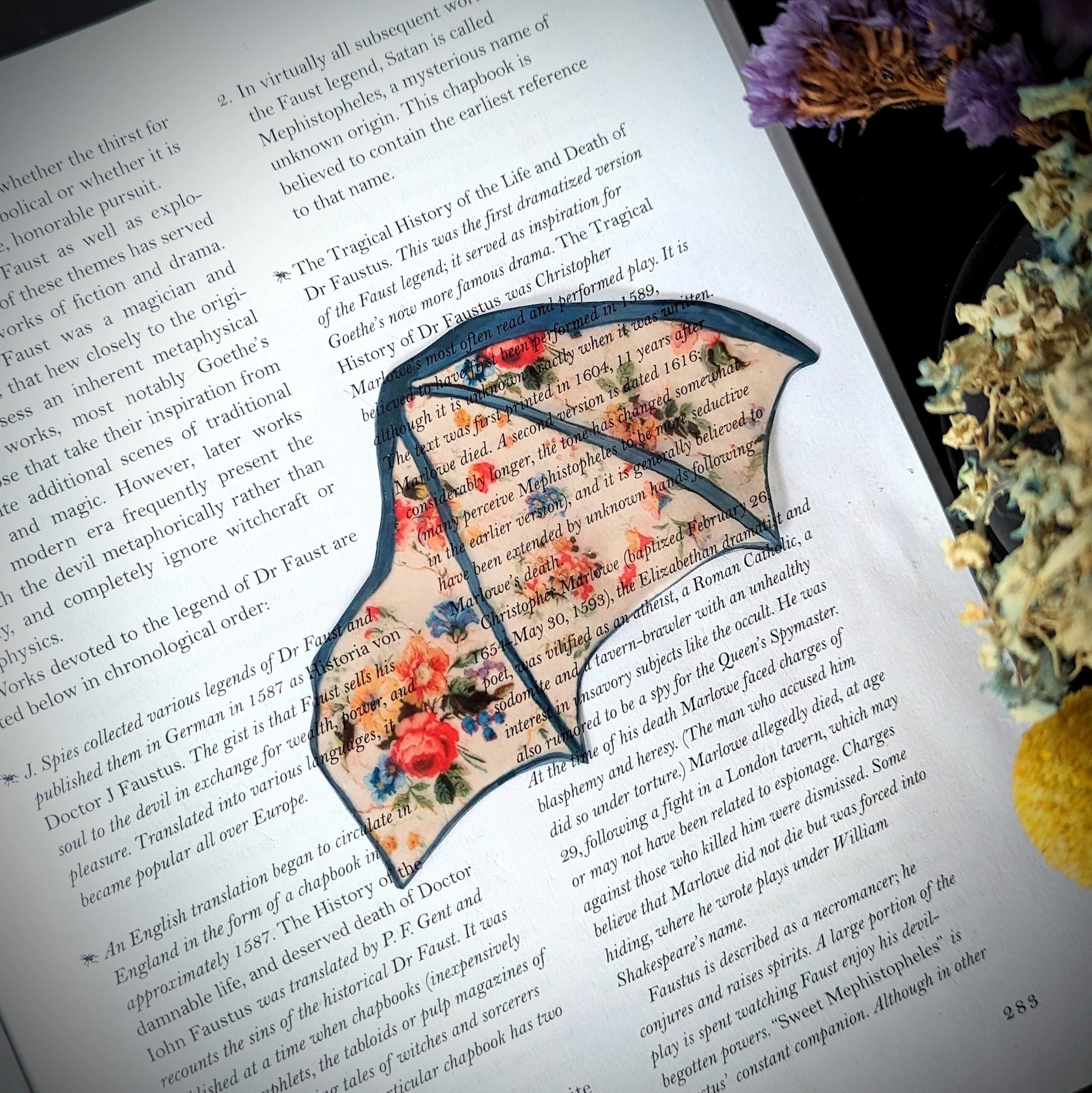 a photo of a clear bookmark with a floral pattern and designed to look like a bat's wing