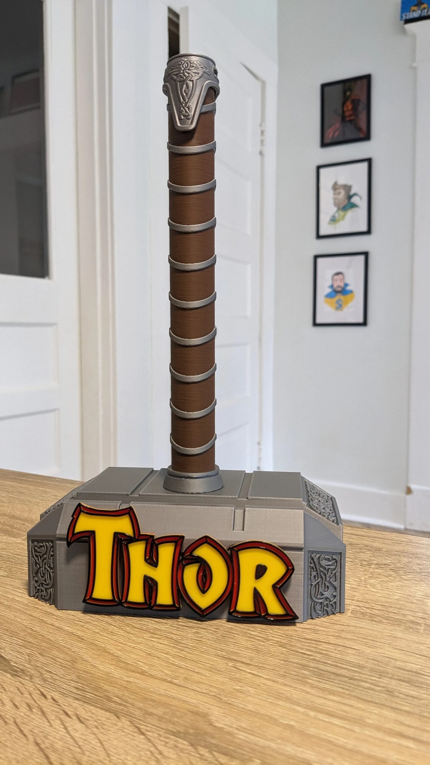 A comic book stand shaped like Thor's hammer. On the hammer head, Thor's name appears in yellow letters.