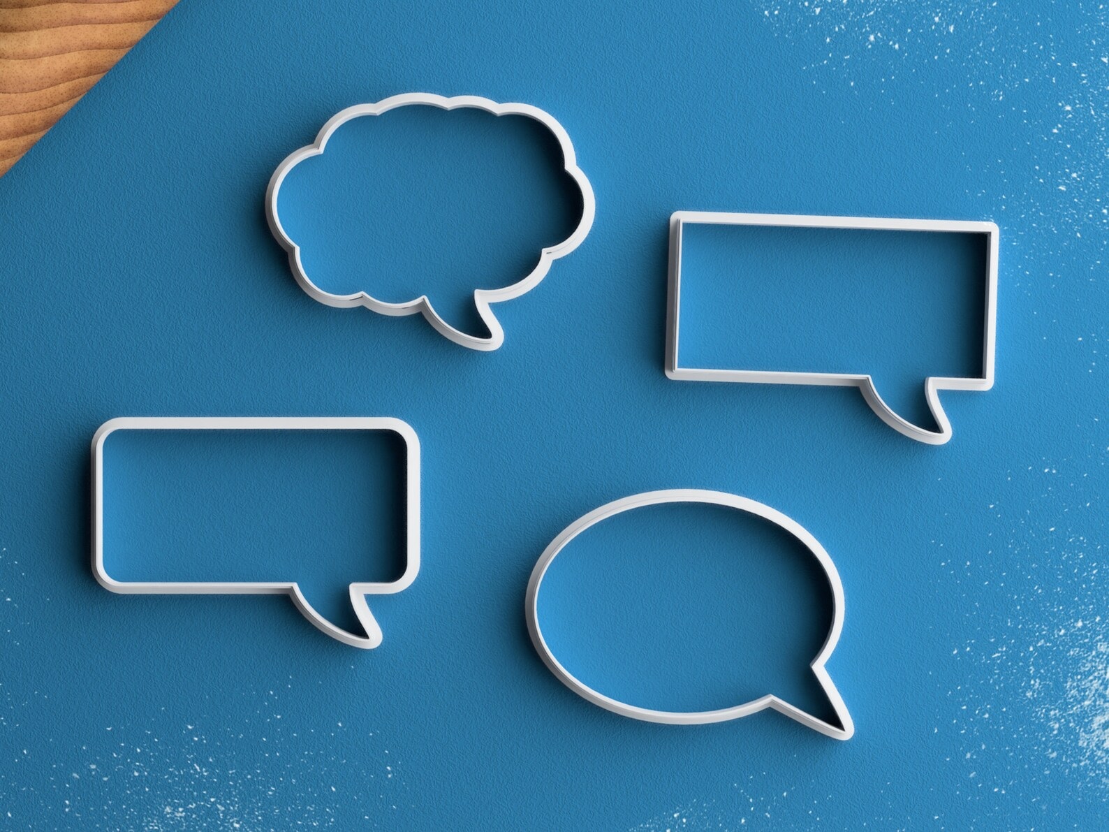 A set of four cookie cutters, each shaped like a thought or speech bubble, against a blue background