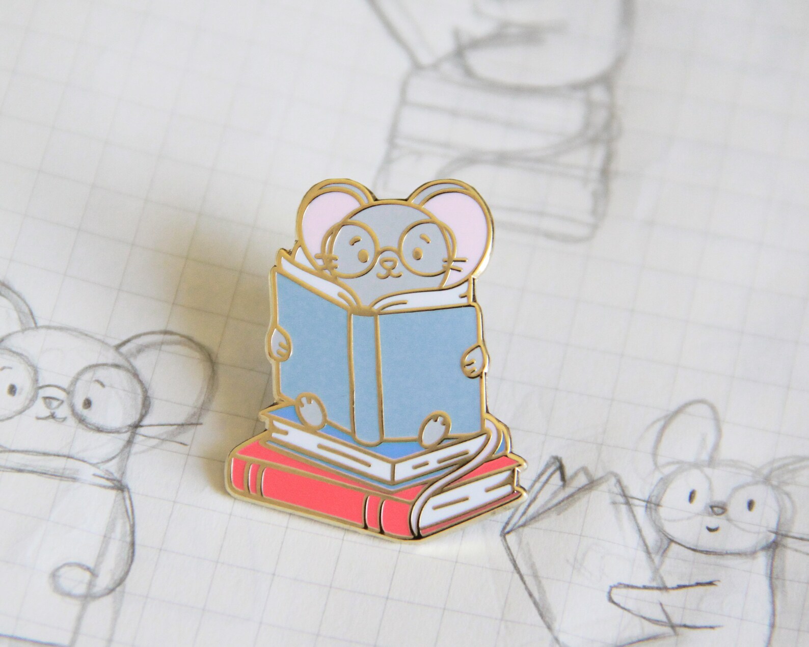 image of an enamel pin with a reading mouse