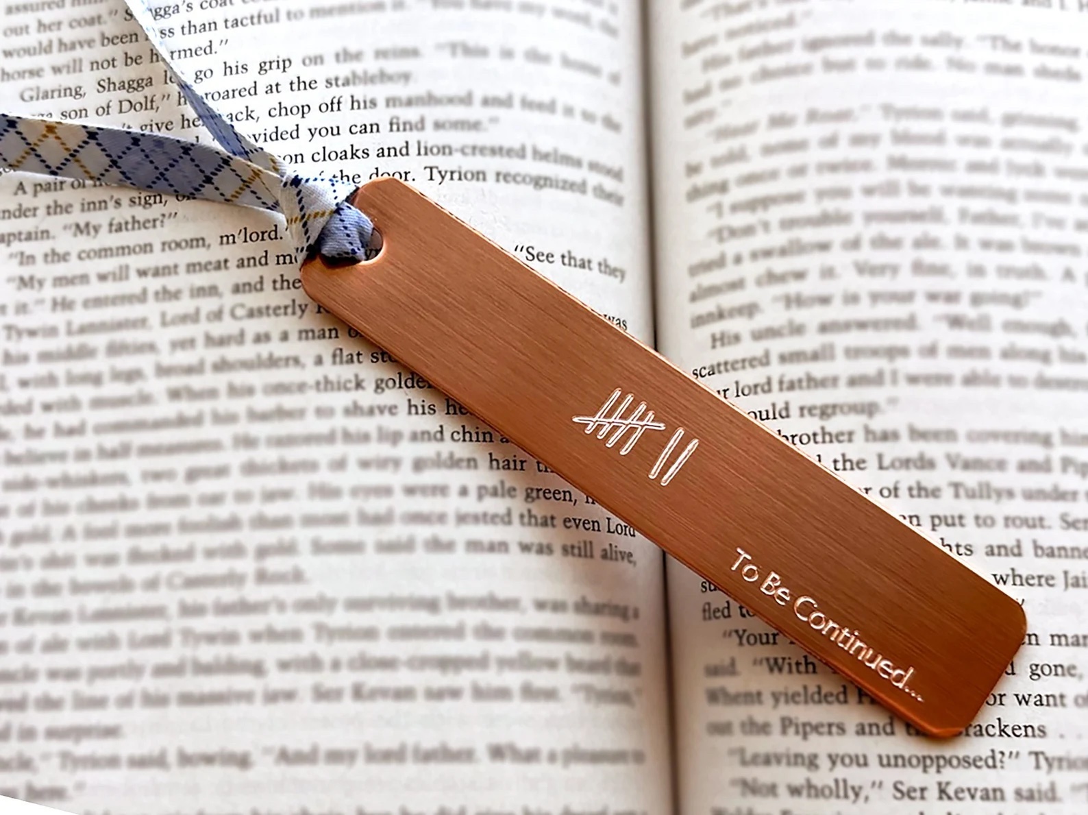 a photo of a copper book mark with the words "to be continued" engraved on the side.