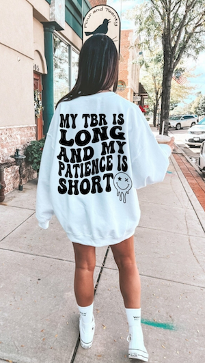 a white sweatshirt with bubble black font on back printed to say " My tbr is long, but my patience is short"