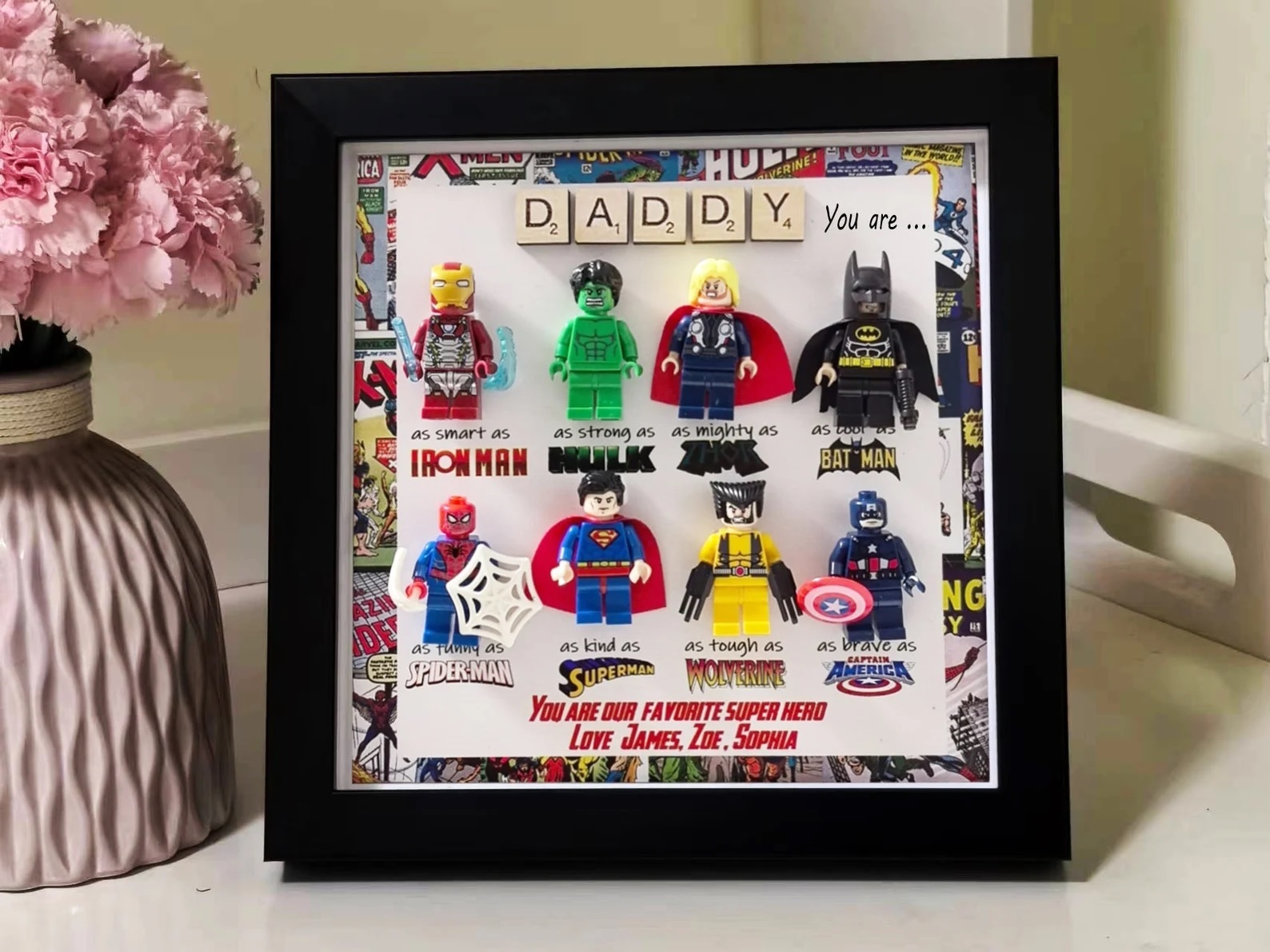 A black frame containing eight mini Lego figures of superheroes. Text addressed to "Daddy" reads "You are our favorite superhero."